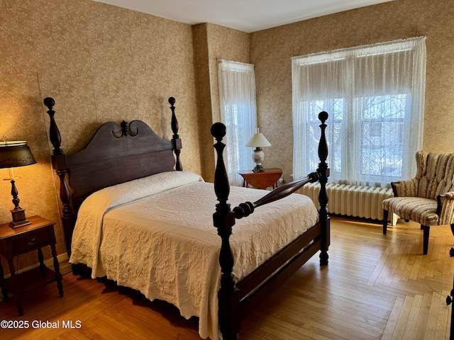 bedroom with wallpapered walls, radiator heating unit, and wood-type flooring