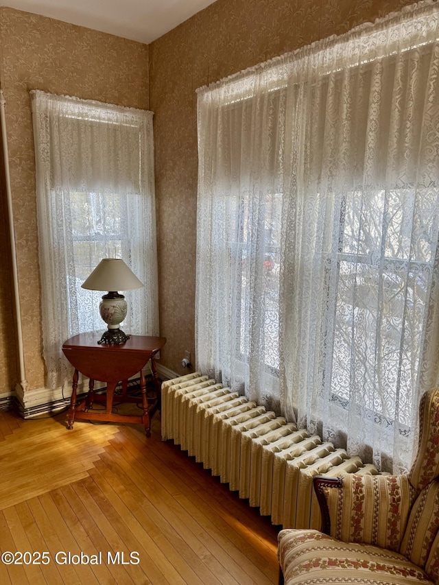 sitting room with radiator, wallpapered walls, baseboards, and hardwood / wood-style flooring