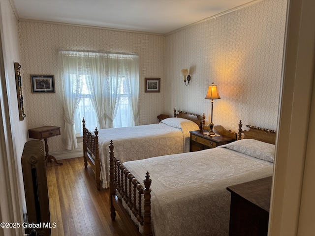 bedroom with radiator, baseboards, wallpapered walls, ornamental molding, and wood-type flooring