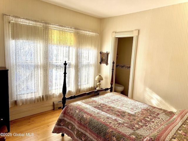 bedroom with a baseboard radiator, multiple windows, and hardwood / wood-style floors