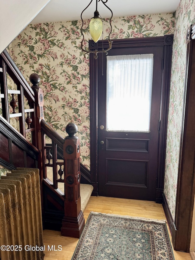 entrance foyer with wallpapered walls, stairs, baseboards, and wood finished floors