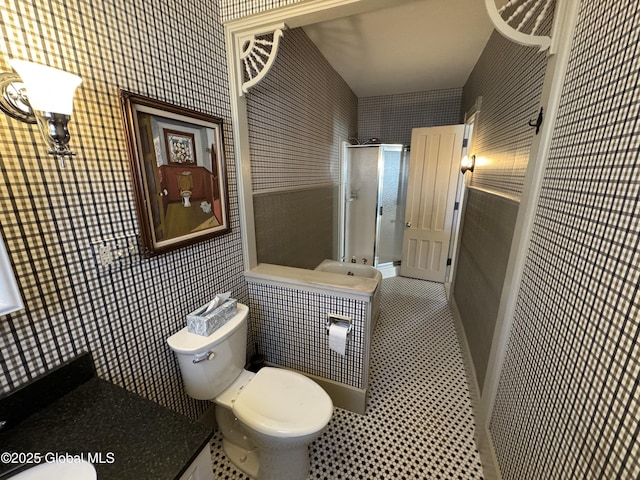 full bathroom featuring wallpapered walls, tile walls, toilet, and a stall shower