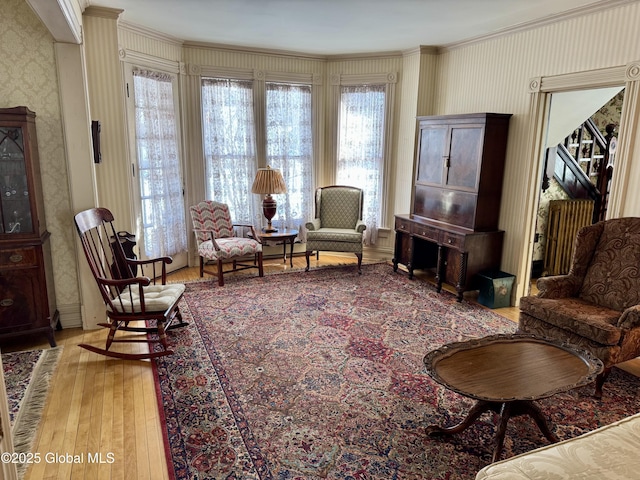 sitting room featuring ornamental molding, wallpapered walls, and hardwood / wood-style flooring