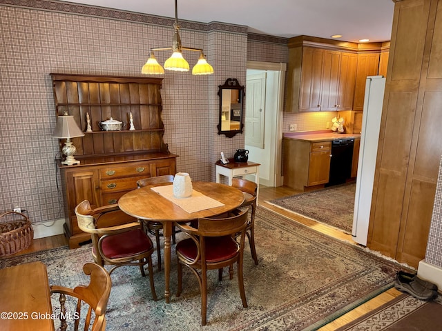 dining area with light wood-type flooring and wallpapered walls