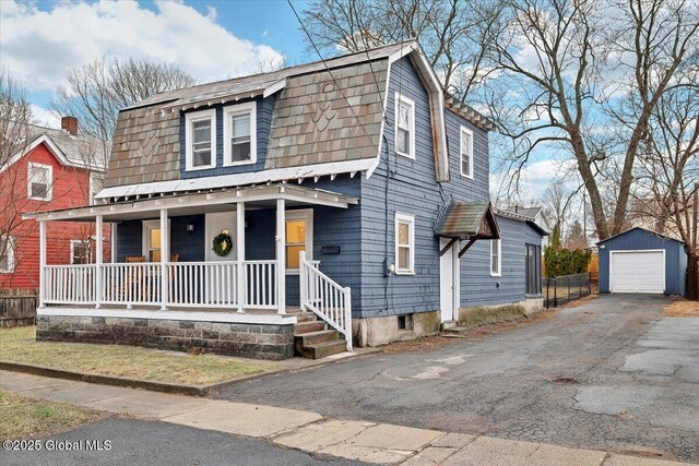 view of front of home with a garage, a gambrel roof, driveway, covered porch, and an outdoor structure