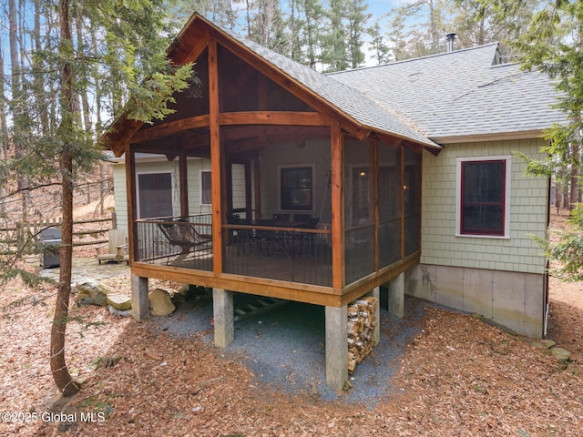 exterior space featuring roof with shingles and a sunroom