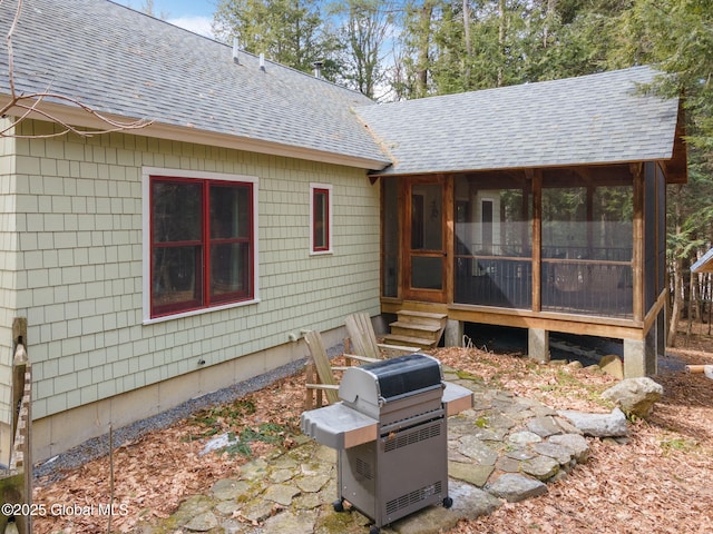 rear view of property featuring roof with shingles and a sunroom