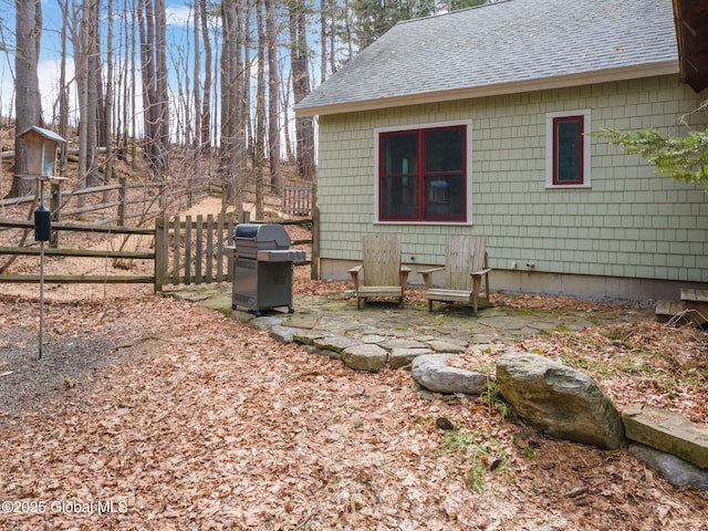 exterior space featuring a shingled roof and fence