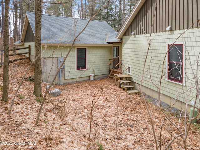 view of home's exterior with a shingled roof and fence