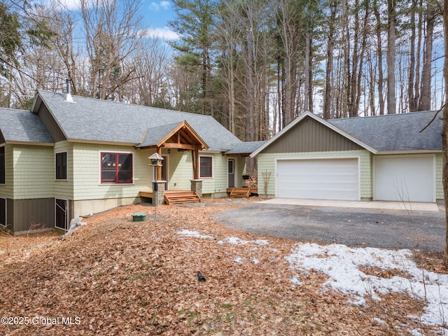 view of front of property with driveway, a garage, and roof with shingles