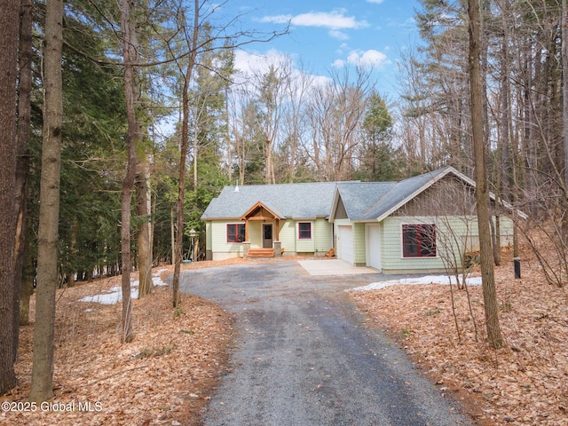 view of front facade featuring aphalt driveway, a garage, and roof with shingles