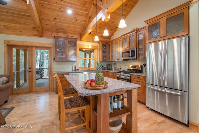 kitchen with brown cabinetry, lofted ceiling with beams, stainless steel appliances, glass insert cabinets, and light wood-style floors