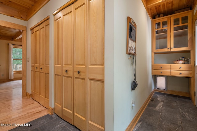 corridor featuring baseboards, wood finished floors, and wooden ceiling