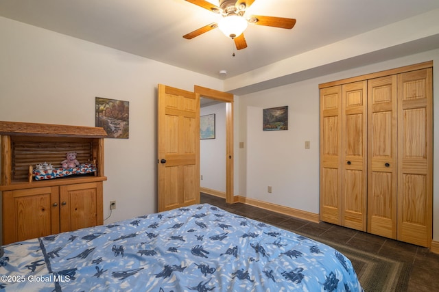 bedroom featuring dark tile patterned floors, a ceiling fan, baseboards, and a closet