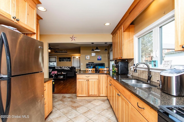 kitchen with a peninsula, freestanding refrigerator, a sink, open floor plan, and backsplash