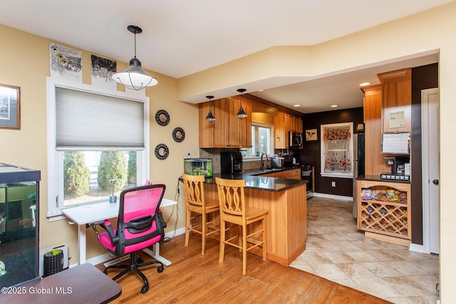 kitchen featuring stainless steel microwave, plenty of natural light, a peninsula, and a sink