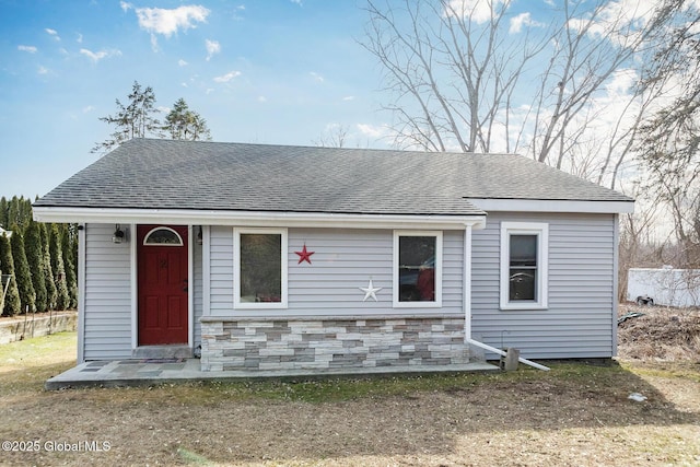 view of front facade with stone siding and roof with shingles