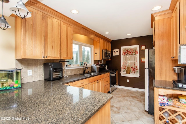 kitchen with a sink, dark stone countertops, backsplash, recessed lighting, and appliances with stainless steel finishes