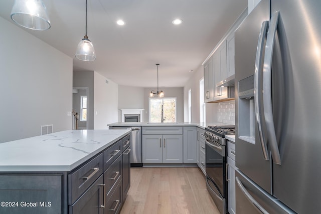 kitchen with under cabinet range hood, tasteful backsplash, stainless steel appliances, light wood-style floors, and a peninsula