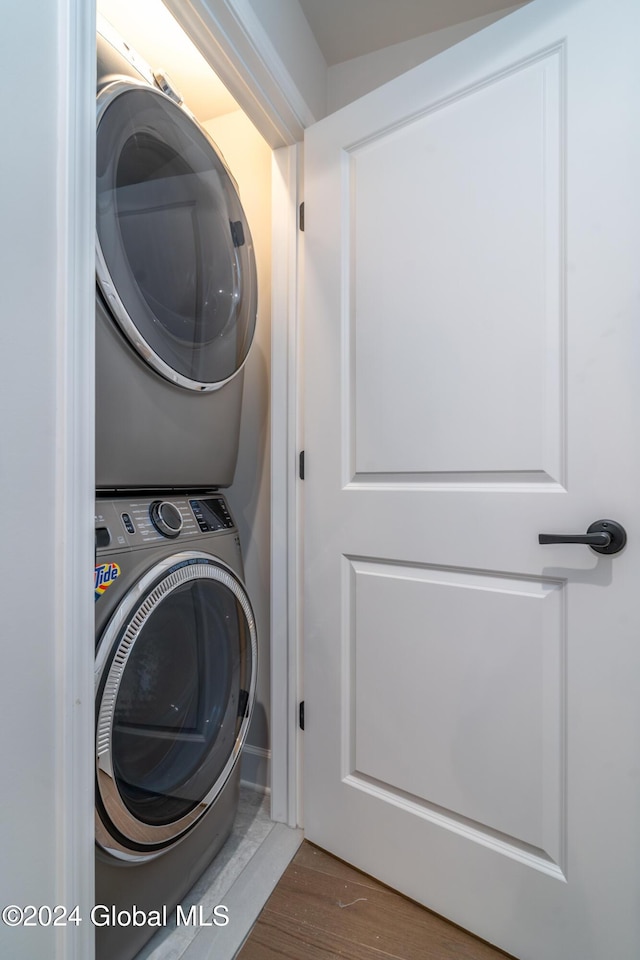 laundry room with stacked washer and dryer, wood finished floors, and laundry area