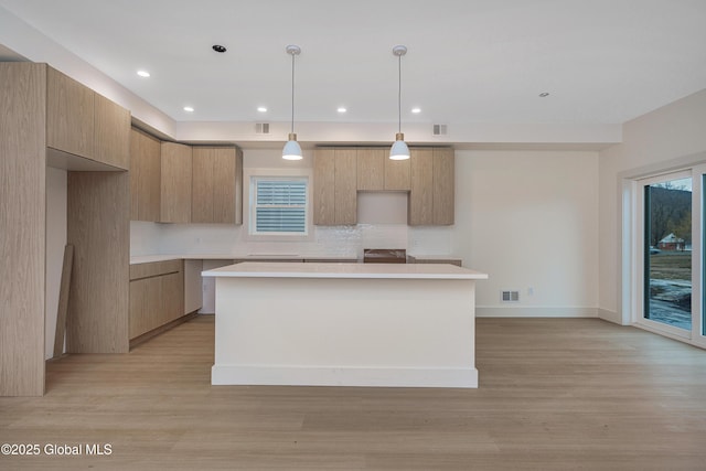 kitchen featuring visible vents, light wood-style flooring, modern cabinets, backsplash, and a center island