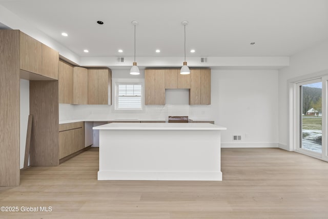 kitchen with a center island, light wood finished floors, modern cabinets, and light countertops