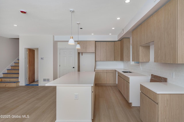 kitchen with a kitchen island, visible vents, light wood-style flooring, and modern cabinets