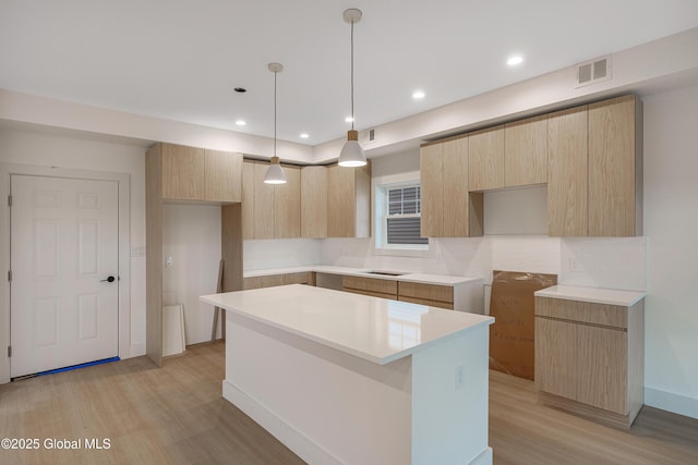 kitchen featuring light brown cabinetry, visible vents, a kitchen island, and modern cabinets