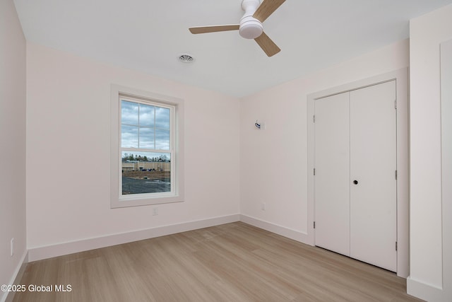 unfurnished bedroom featuring light wood-type flooring, visible vents, baseboards, and a closet