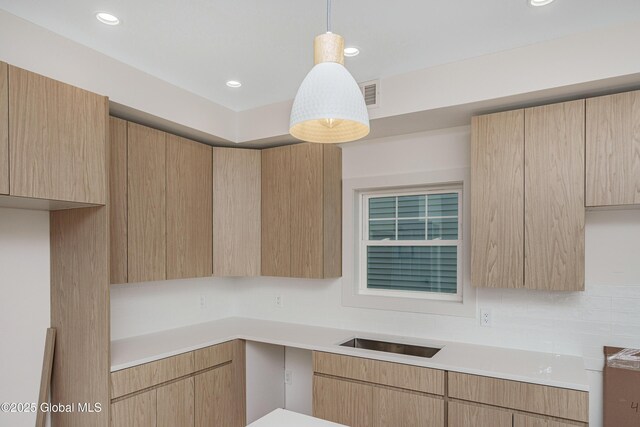 kitchen with light brown cabinets, recessed lighting, hanging light fixtures, light countertops, and modern cabinets