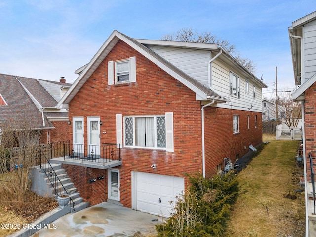 rear view of property featuring a garage, brick siding, a lawn, and fence