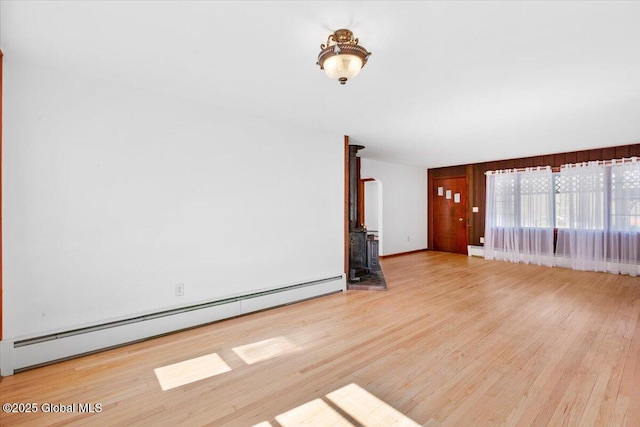 empty room featuring a baseboard heating unit and wood finished floors