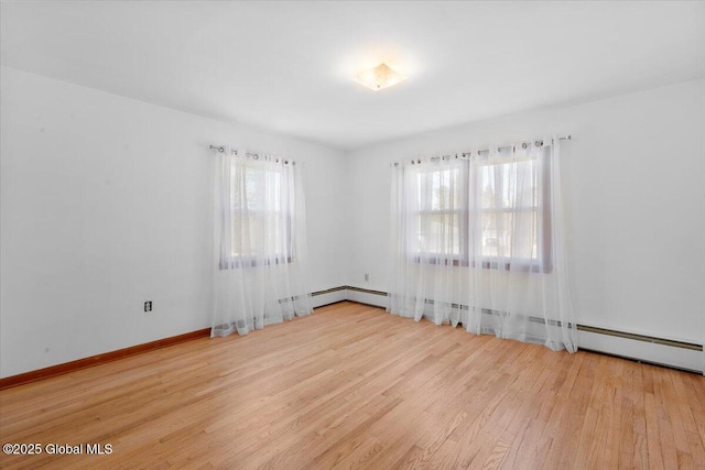 empty room featuring a wealth of natural light, baseboards, and wood finished floors