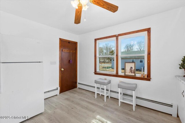 interior space featuring light wood-type flooring, a ceiling fan, and a baseboard radiator