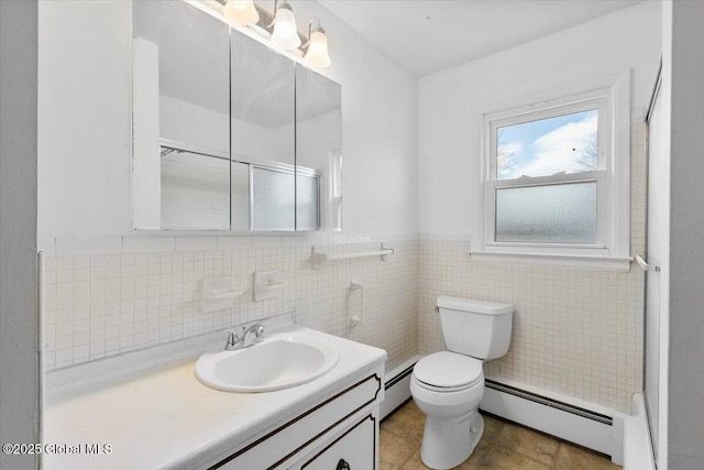 full bath featuring tile walls, vanity, toilet, and a baseboard heating unit