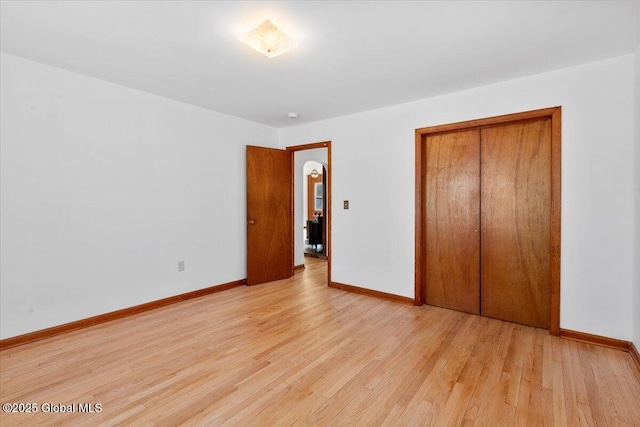 unfurnished bedroom featuring light wood finished floors, a closet, and baseboards