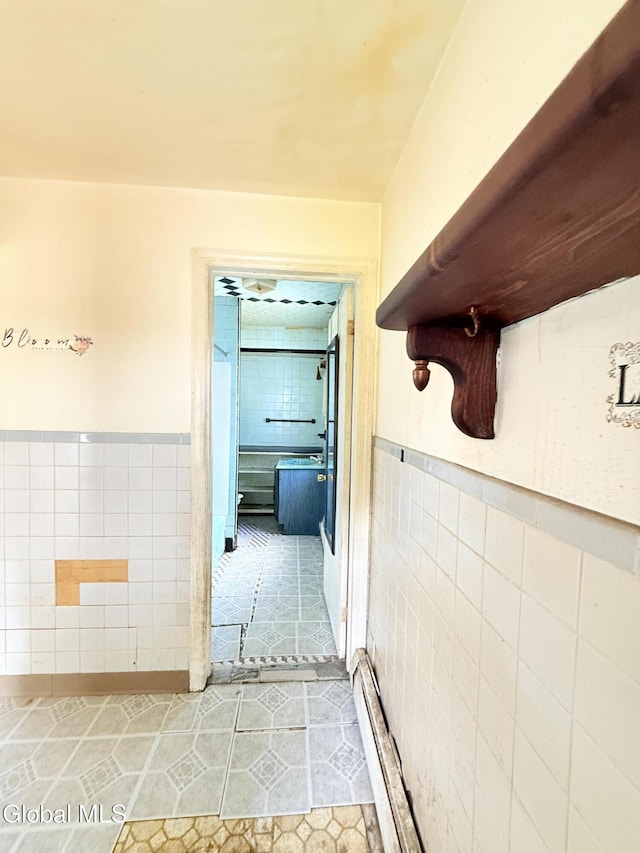 3144 N Thompson St, Rotterdam, NY 12306 - hall with tile walls, light tile patterned floors, a baseboard radiator, and a wainscoted wall