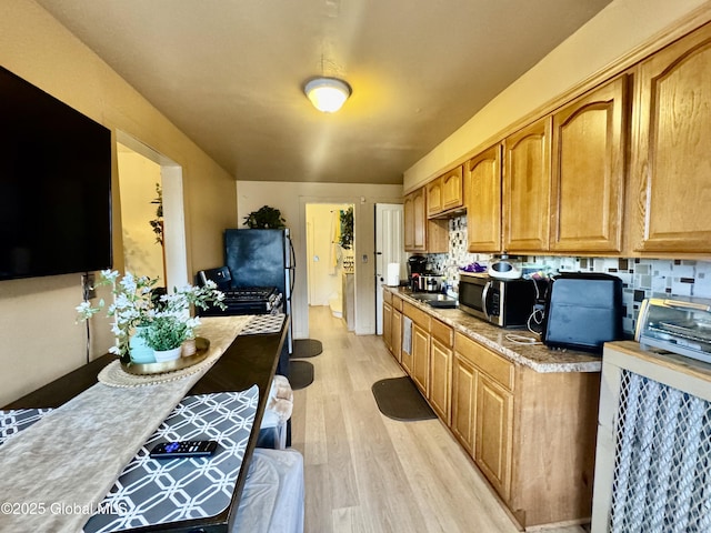 kitchen featuring stainless steel appliances, light countertops, light wood-style floors, brown cabinets, and backsplash