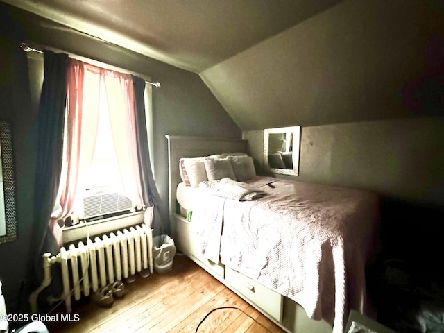 bedroom with cooling unit, lofted ceiling, hardwood / wood-style floors, and radiator heating unit