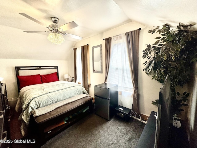 bedroom with dark colored carpet, a ceiling fan, freestanding refrigerator, and vaulted ceiling