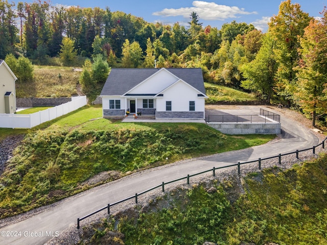 view of front of home featuring stone siding, a front lawn, and fence