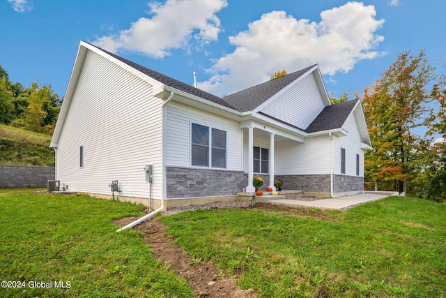 view of side of property featuring central air condition unit, a yard, stone siding, and a shingled roof