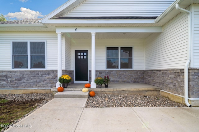 view of exterior entry featuring stone siding and a porch