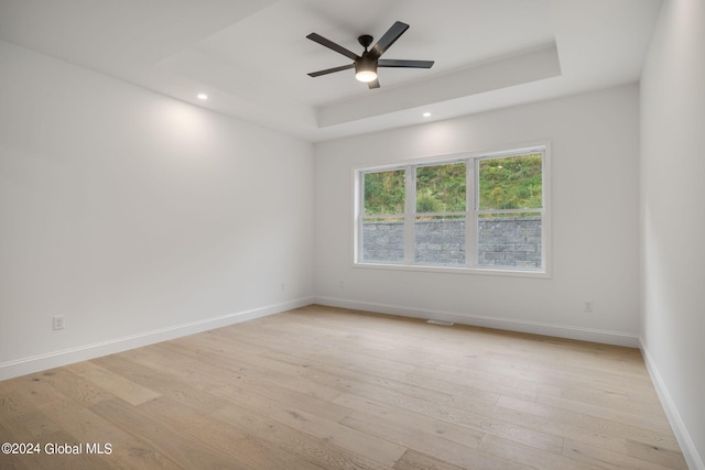 unfurnished room featuring baseboards, light wood-type flooring, recessed lighting, a raised ceiling, and a ceiling fan