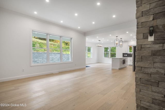 living area with baseboards, light wood-style floors, an inviting chandelier, and crown molding