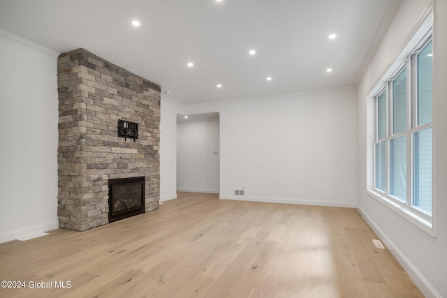 unfurnished living room featuring visible vents, crown molding, baseboards, a fireplace, and light wood-style floors