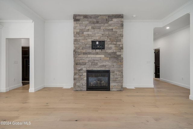 unfurnished living room featuring light wood-type flooring, baseboards, a stone fireplace, and ornamental molding