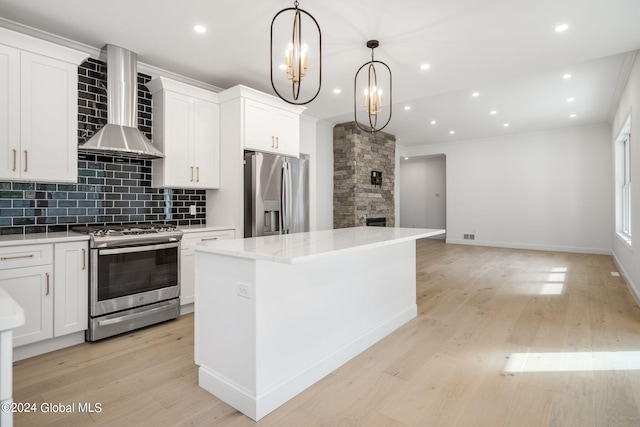 kitchen featuring light wood-style flooring, a center island, a stone fireplace, appliances with stainless steel finishes, and wall chimney exhaust hood