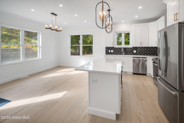 kitchen featuring tasteful backsplash, light countertops, ornamental molding, stainless steel appliances, and white cabinetry