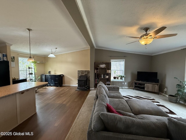 living room featuring lofted ceiling, a textured ceiling, a wood stove, and crown molding